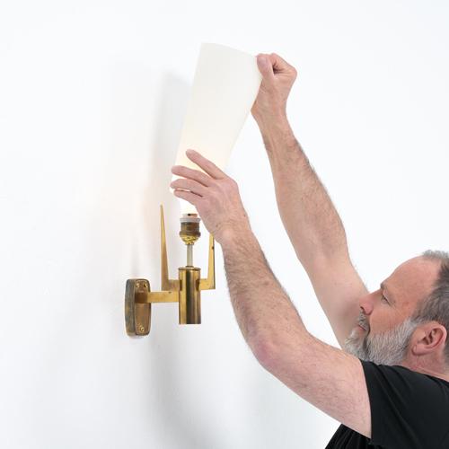 This elegant wall lamp was made by Stilnovo around the 1950s. It has a brass frame, supporting an opaline glass shade....