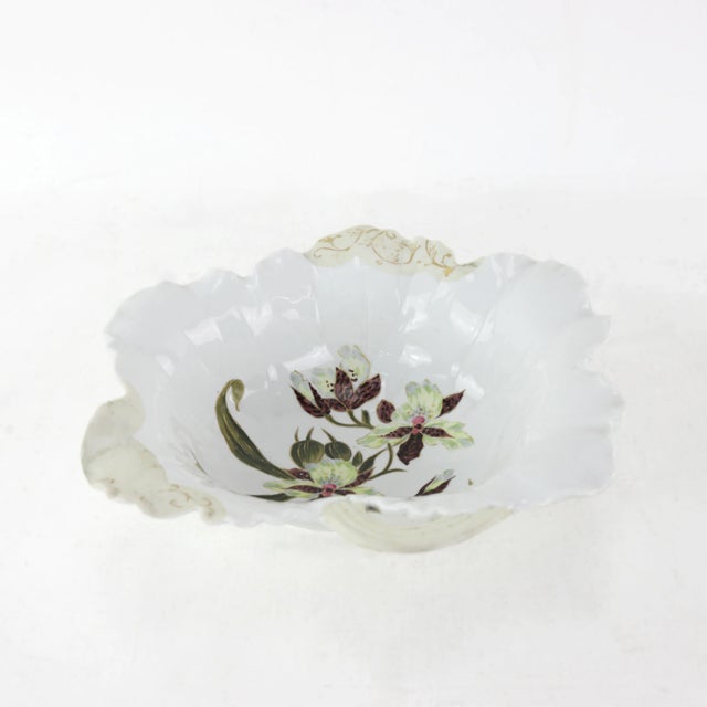 This stunning Victorian-era porcelain dish captivates with its ornate shape and hand-painted orchid floral motif....
