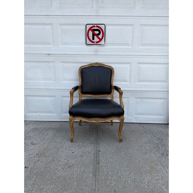 We have a vintage Louis XV style armchair with black upholstery and an ornate carved wood frame for sale. This beautiful...