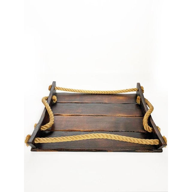 French serving tray dating from the 1990s, crafted from dark-stained wood and accented with thick natural rope. The...