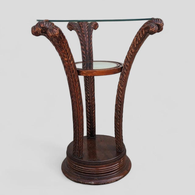 An early 20th-century Art Nouveau side table with a circular glass top, carved wood pedestal base, and a smaller round...