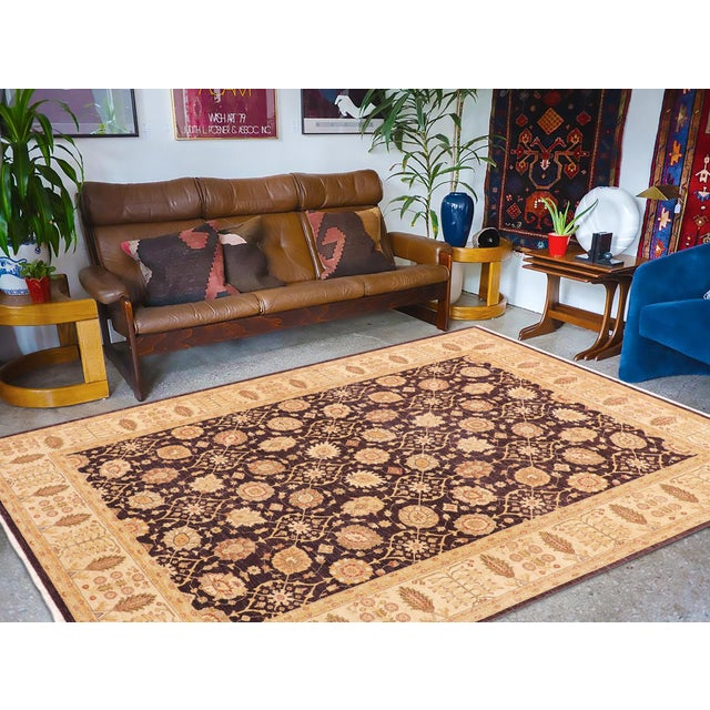 Gold blossoms sit in a neat trellis across a dark aubergine field, framed by a wide beige border. The regular repeat gives...