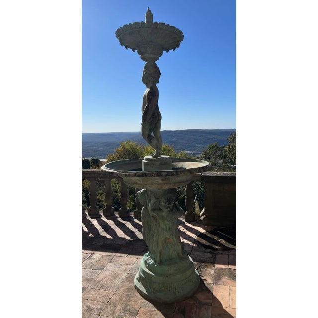 Monumental Bronze Cherub Fountain. This extraordinary two-tier, one piece cast bronze fountain features beautifully...