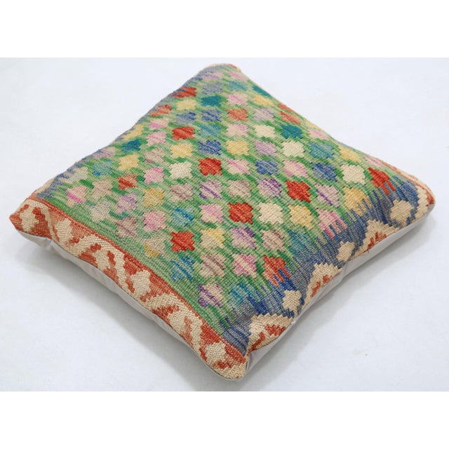A one-of-a-kind handwoven Afghan wool kilim accent pillow featuring a diamond lattice grid in vivid green, red, and blue....