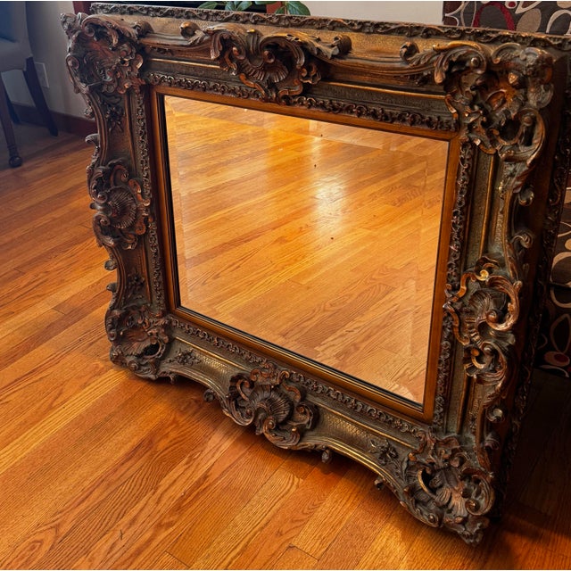 Large Baroque Rococo style wall mirror featuring an exceptionally ornate gilt frame with dramatic scrolling carvings,...