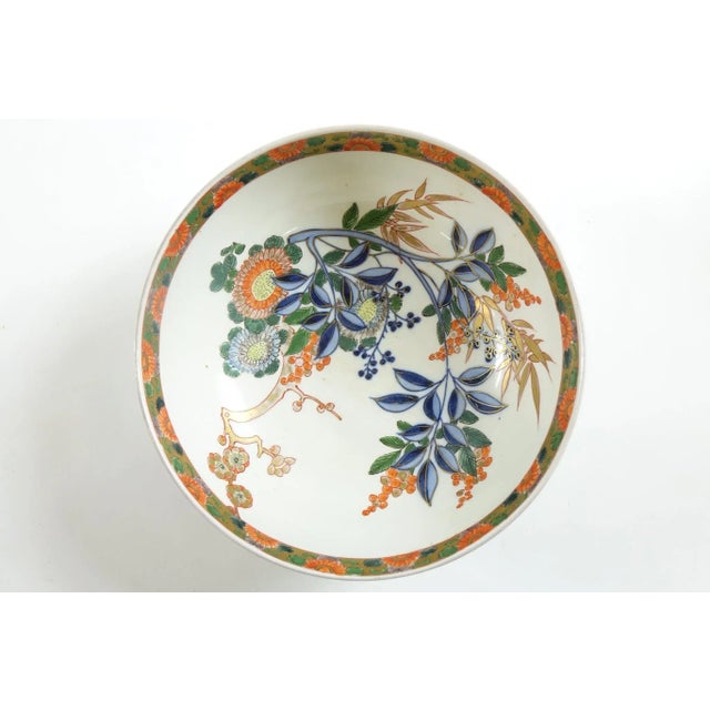 This antique Japanese bowl is a beautiful example of traditional porcelain artistry, adorned with a delicate floral design...