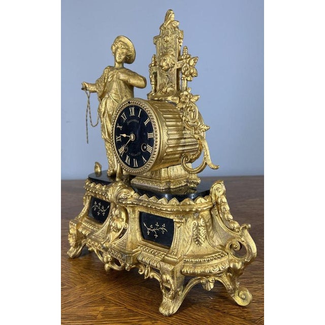 This striking Antique French figural mantel clock , richly ornamented in the Neo-Rococo / Louis XV style, features an...