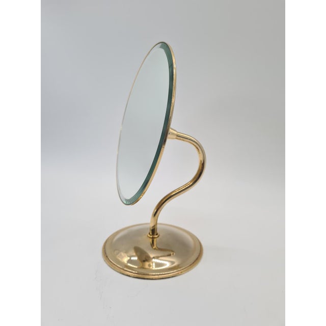 A stylish, decorative table mirror with an adjustable tilt angle, mounted on an elegant, wavy base. The entire piece is...