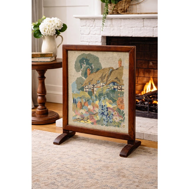 Antique needlepoint fire screen featuring a picturesque thatched cottage garden scene, hand-stitched with rich, softly...
