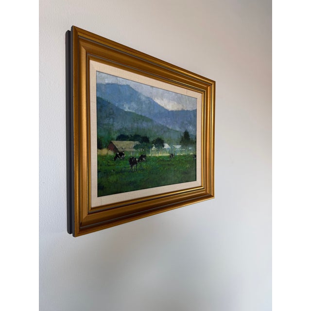 A charming vintage oil on canvas board depicting a peaceful rural farm landscape with grazing cows set against rolling...