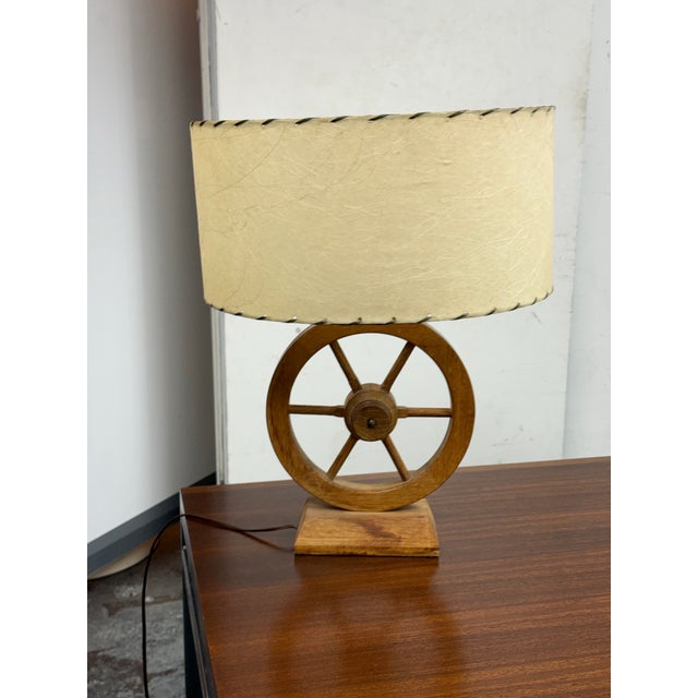 Design Plus Gallery presents a Rustic Wagon-Wheel Table Lamp. This table lamp showcases a wooden wagon-wheel base set on a...