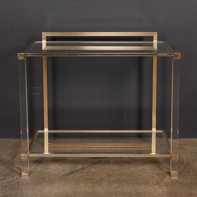 A vintage 20th century acrylic glass and brass console table by pierre vandel of paris, featuring two glass shelves. The...