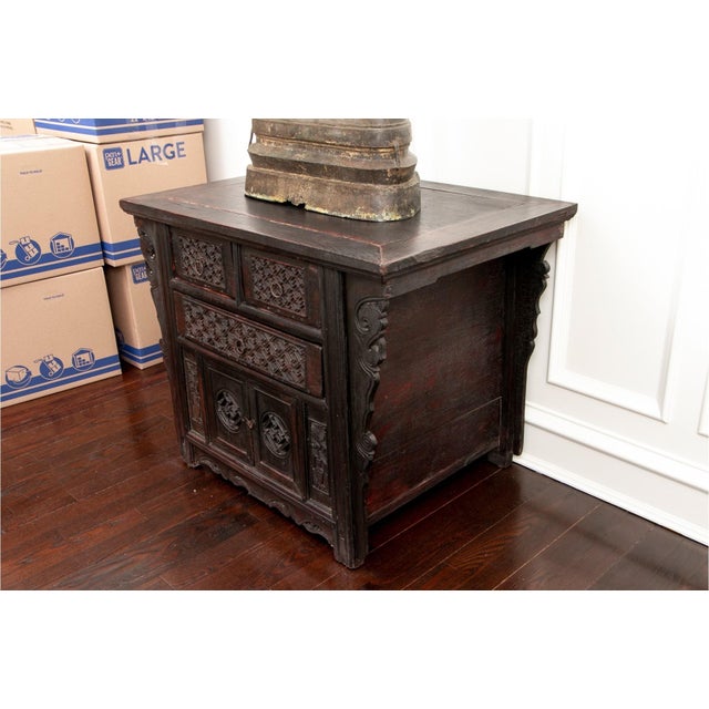 A 19th century Chinese Ming dynasty style butterfly cabinet with carved floral spandrels, drawers, doors in a dark patina...