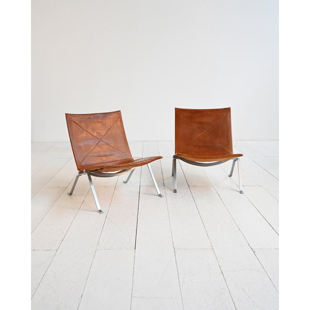Pair of "pk22" armchairs with a brushed steel frame and a suspended cognac-colored leather seat. Designed by poul kjærholm...