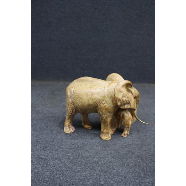 Composite elephant sculpture featuring a mother and calf standing closely together with detailed texturing and curved...