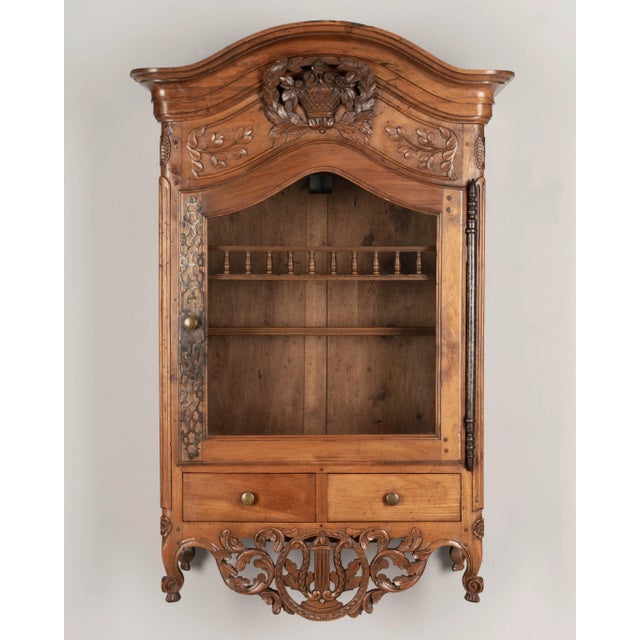 A late 18th century Louis XV style French Provençal verrio, or wall display cabinet from Nîmes. Made of solid walnut with...