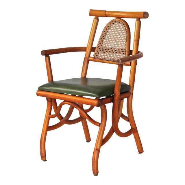 Vintage rattan armchair with caned backrest and green vinyl seat.