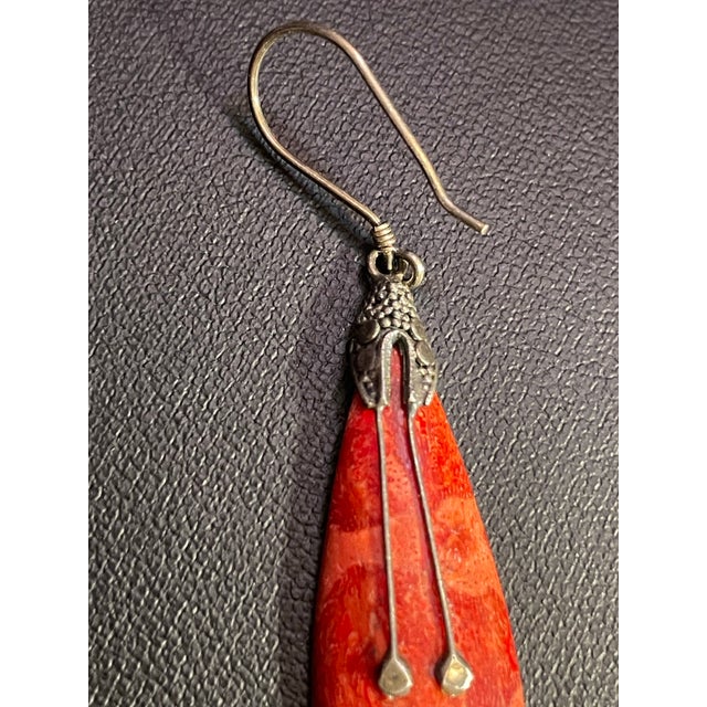 Long dangle earring with ornate sterling design draping over long teardrop shaped spiny oyster. Overlay decorative...