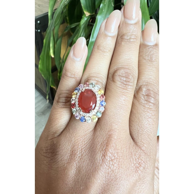 This eye-catching cocktail gemstone ring showcases a stunning 4.35 Carat Oval Cut Natural Red Fire Opal as its...