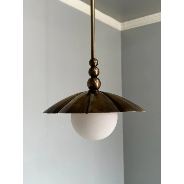 Elevate your space with this elegant handcrafted pure brass pendant light. Featuring a fluted dome shade and a matte white...