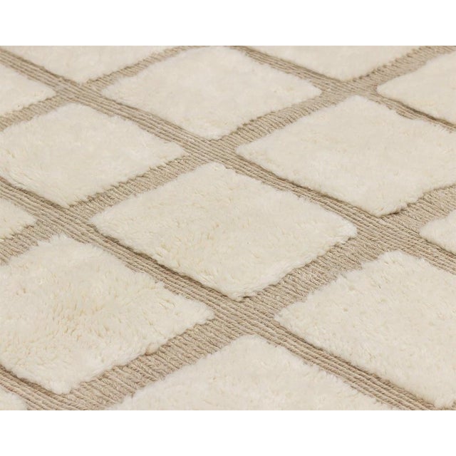 Sophisticated hand-knotted wool rug featuring a grid pattern in natural Ivory and Taupe, with handwoven detailing for a...