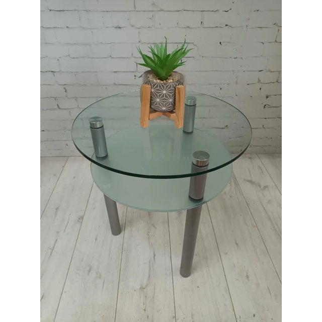 This elegant piece is a contemporary round, two-tiered side table or plant stand from the 1980s, featuring a beautiful...