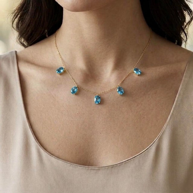 Radiating elegance and brilliance, this Swiss Blue Topaz Dangle Station Necklace features five captivating oval-cut Swiss...