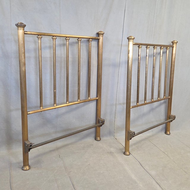 A charming pair of antique or vintage brass headboards for twin beds. They have an aged, distressed patina from age and...
