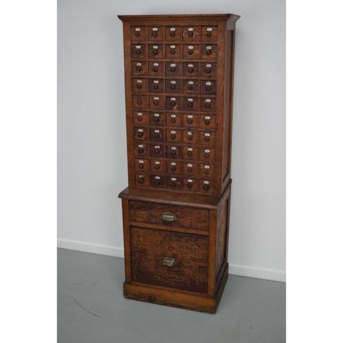 This cabinet was made in france from oak in the early 20th century. It features 50 small drawers with enamel numbers and 2...