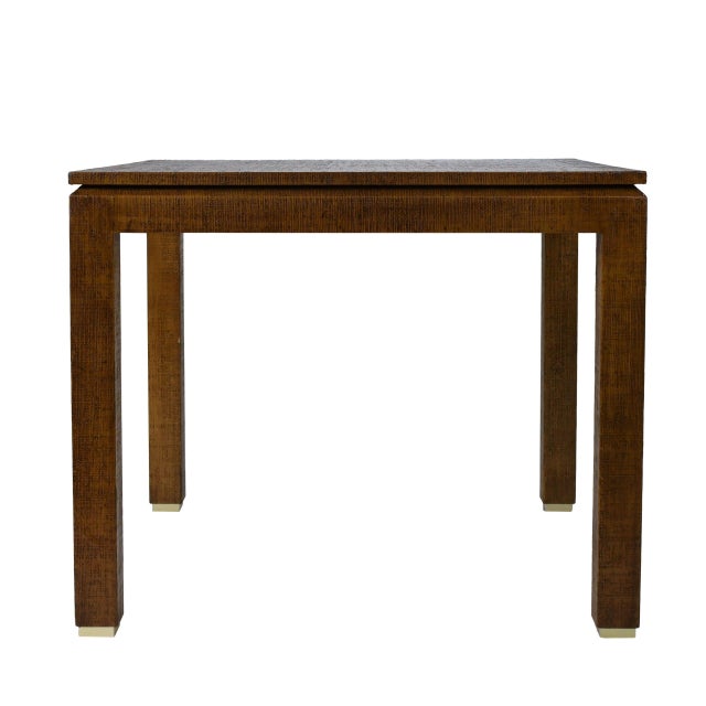 A square grasscloth game table with brass cap feet and a rich newly lacquered finish. The textured grasscloth top brings...