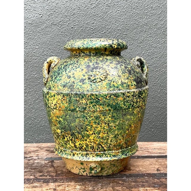 This vintage speckled pottery vessel showcases a bold, exuberant glaze technique, its rounded, amphora-like body enveloped...