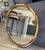 Round antique 1930s French Rococo style gold giltwood wall mirror featuring leafy scroll carvings.