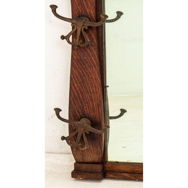 Arts and Crafts Oak Hat Rack Wall Mirror, with four double metal coat hanger hooks. 28" H x 45" W x 5" D. Provenance: From...