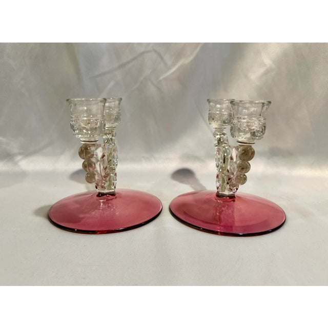 A pair of Art Deco era double candle holders with cranberry flash bases. 6.75” w x 6” deep x 6” h, bases 6” diameter.