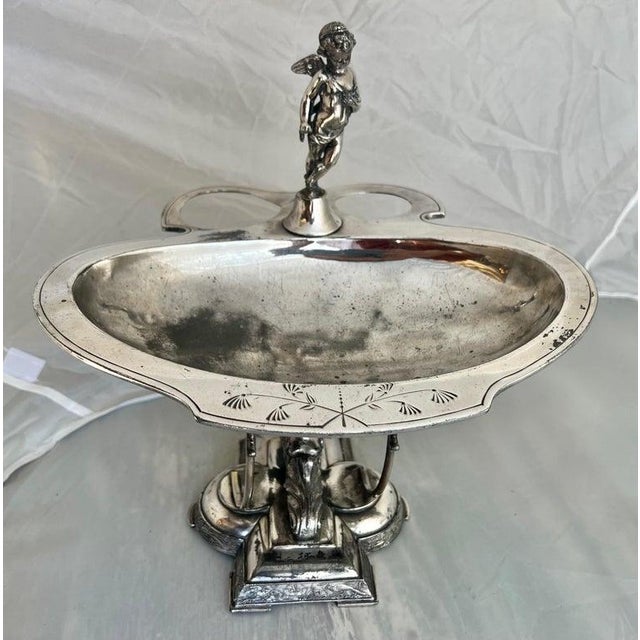 The Wilcox Silver Plate serving dish features a finely detailed angel and winged figure adornments along with acanthus...