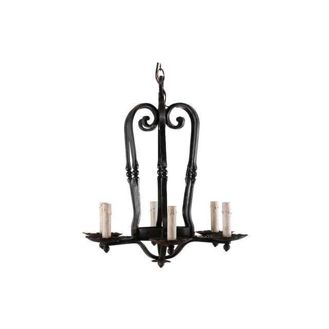 A vintage French six-light black iron chandelier. This French light fixture from the mid 20th century features an...