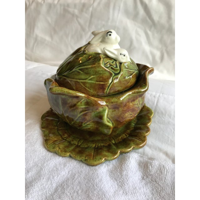 Cabbage shaped covered bowl with under plate has 3 bunnies peeking from under the leaves on the lid.