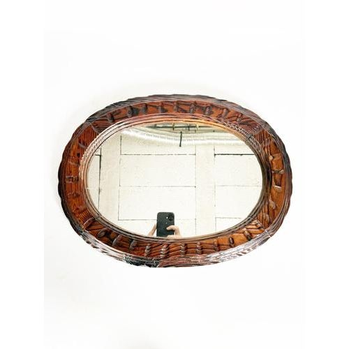 Charming carved wooden wall mirror dating from the 1960s, inspired by the chalet style. Its dark brown oval wooden frame...
