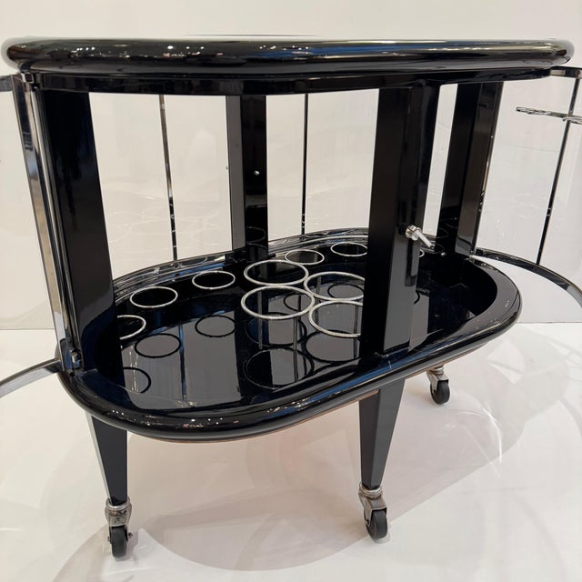 A Modernist ebonized bar cart. Black lacquer with polished nickel details, glass top with mirrored outer border and glass...