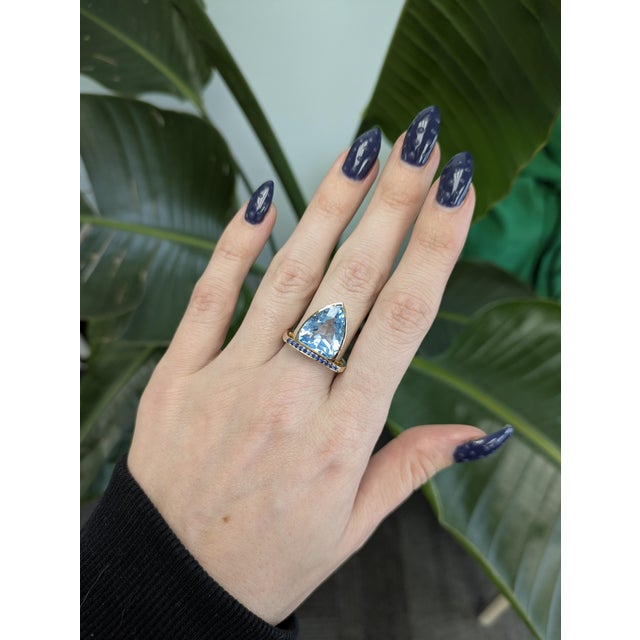 9.5ct Swiss Blue Topaz ring accented with sparkling sapphires, showcasing a bold 15×12.5 mm trillion-cut center stone....