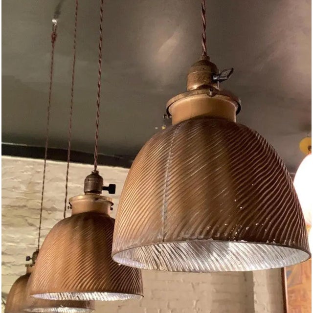 A pair of early 20th century industrial factory pendant lights, featuring x-ray mercury glass dome shades with gold...