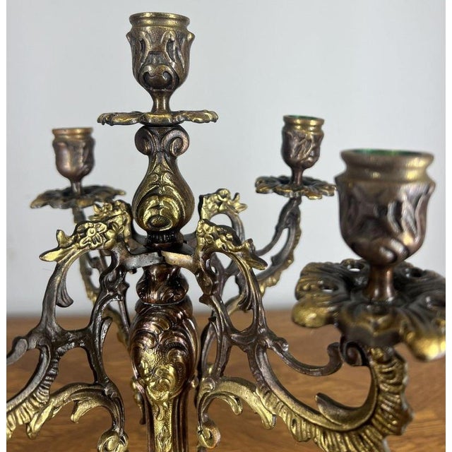 This Vintage French candelabra displays elegant, ornate detailing with scrolling arms, decorative candle cups, and a...