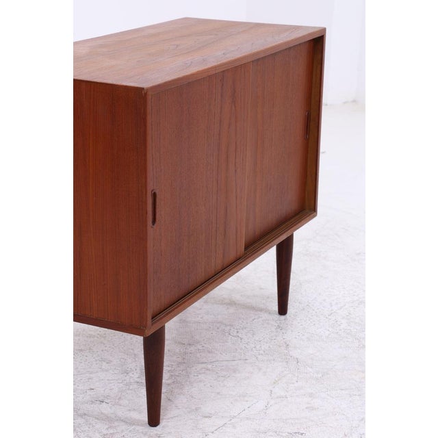 Vintage teak chest of drawers with clean lines and practical sliding doors. The slender, tapered legs and beautiful grain...