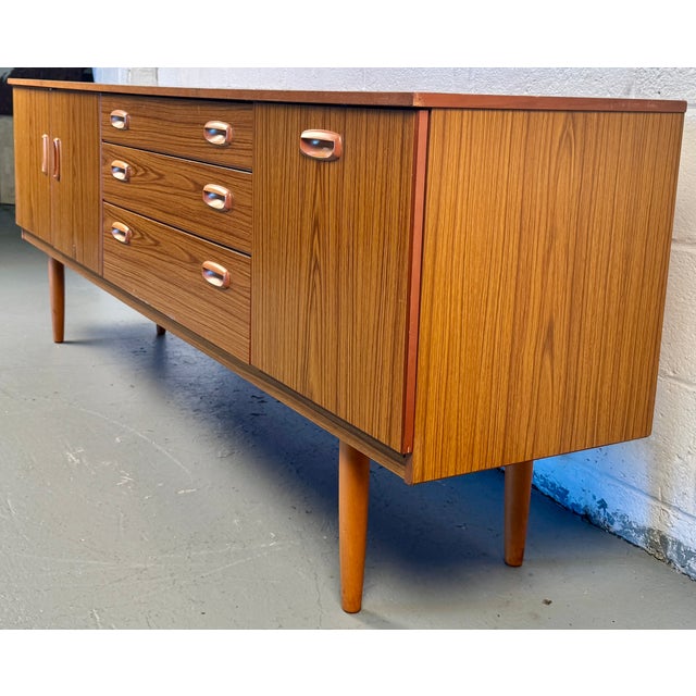 A striking example of 1960s–70s British mid-century craftsmanship, this Schreiber teak sideboard brings refined...