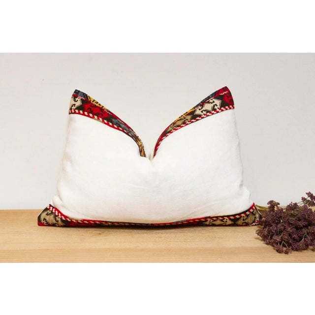 This handcrafted pillow features a vibrant, hand-stitched textile border created by the Lakai tribe of Uzbekistan. It is a...