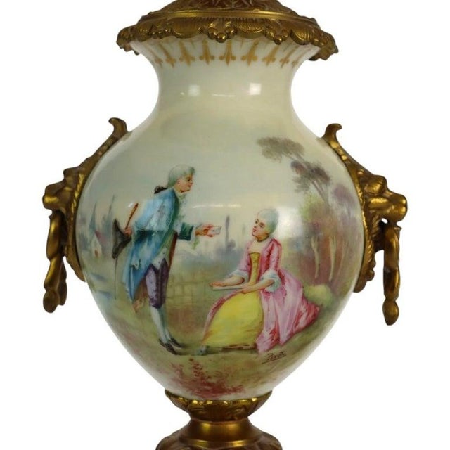 An exquisite antique French Sevres style urn lamp, crafted circa 1890, featuring a finely painted porcelain body mounted...