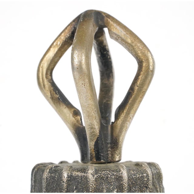 Spanish Colonial style handbell made of cast iron with a textured exterior and brass finish handle. There is a metal wire...