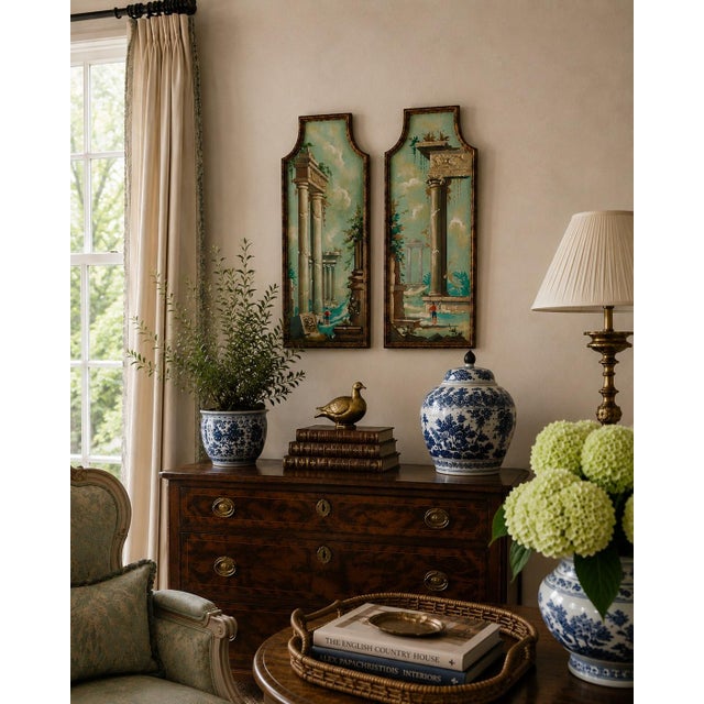 A distinctive pair of Italian capriccio landscapes, painted in oil on shaped panels and presented in softly worn giltwood...