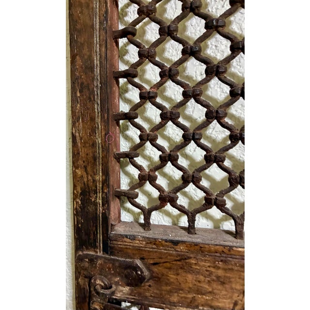 A rare matched pair of antique architectural window shutters featuring hand-forged iron jali latticework set within...