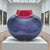 A signed studio-glass vase by Australian artist Maureen Williams, distinguished by a flattened “moon” silhouette and a...